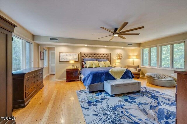 bedroom featuring light wood-style flooring, multiple windows, baseboards, and visible vents