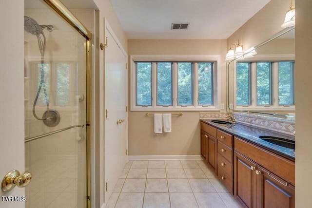 bathroom with visible vents, double vanity, a stall shower, tile patterned floors, and a sink