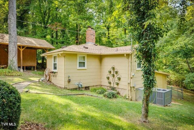 back of property with a yard, central AC unit, a chimney, and fence