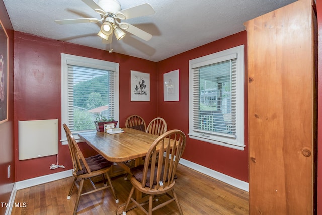 dining room with a ceiling fan, a textured ceiling, baseboards, and hardwood / wood-style floors