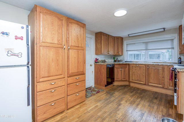 kitchen featuring hardwood / wood-style flooring, electric range, freestanding refrigerator, dishwasher, and brown cabinetry