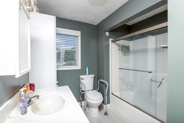 full bathroom featuring toilet, combined bath / shower with glass door, a textured ceiling, vanity, and baseboards