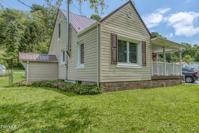 view of side of property with metal roof, a yard, and fence