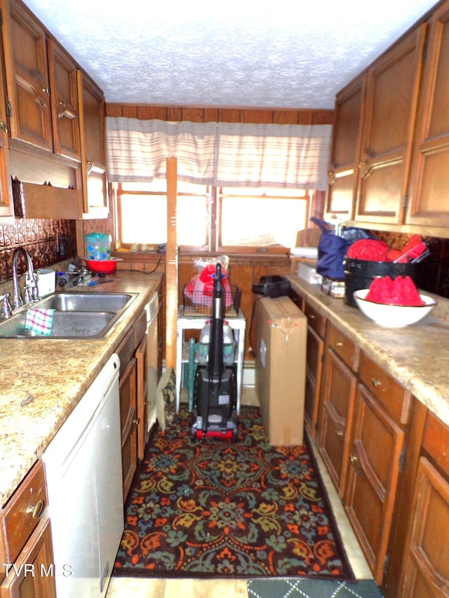 kitchen featuring a sink, a textured ceiling, dishwasher, and brown cabinetry