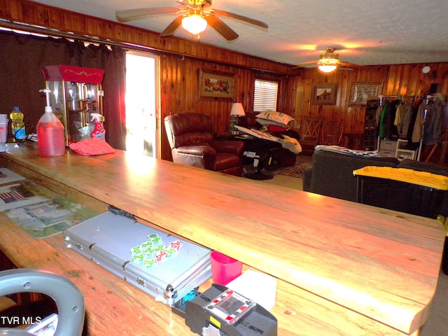 interior space with plenty of natural light, ceiling fan, and wood walls