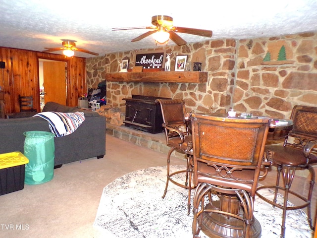 living area with wooden walls, a ceiling fan, and a textured ceiling