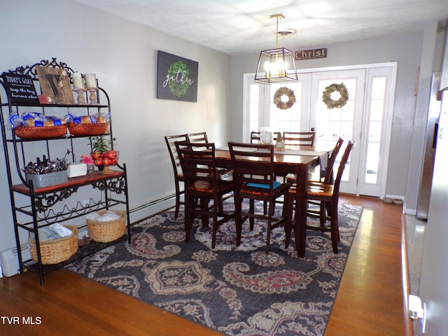 dining space featuring a baseboard heating unit and wood finished floors