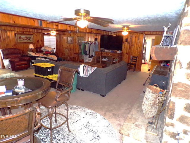 living area with wooden walls, carpet, and ceiling fan