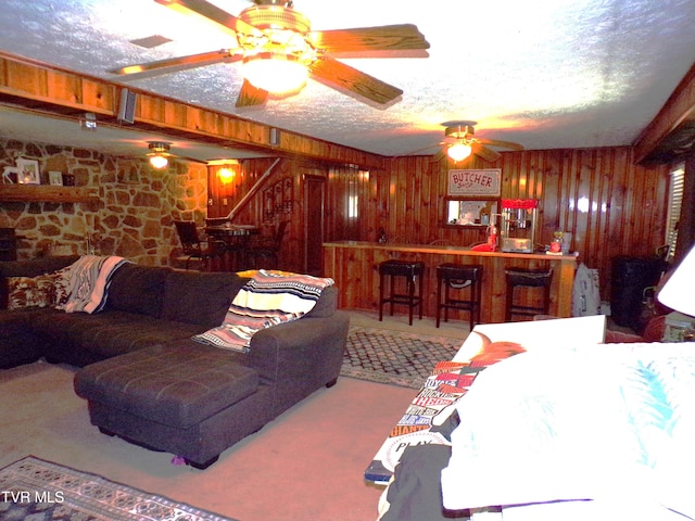 living room featuring wooden walls, a dry bar, a textured ceiling, and stairs