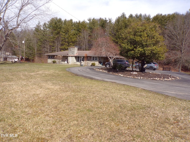 exterior space with aphalt driveway and a wooded view