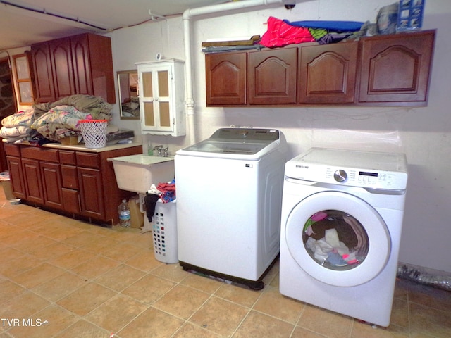 laundry room featuring light tile patterned flooring, a sink, cabinet space, and separate washer and dryer