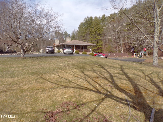 view of yard with aphalt driveway and playground community