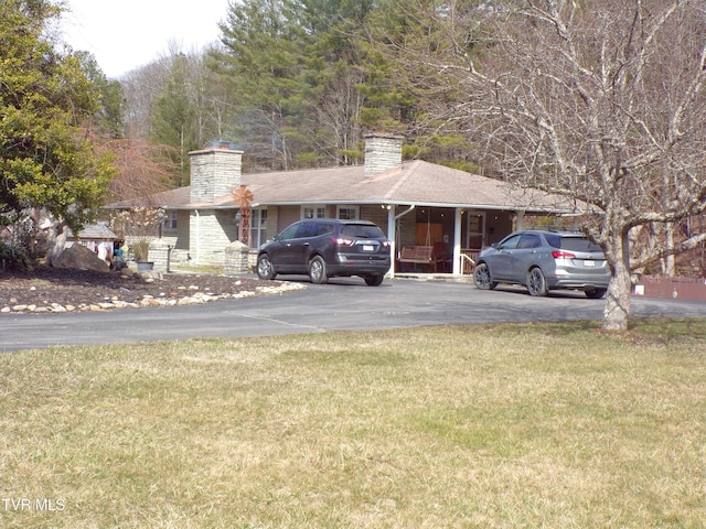 ranch-style home with aphalt driveway, a chimney, and a front lawn