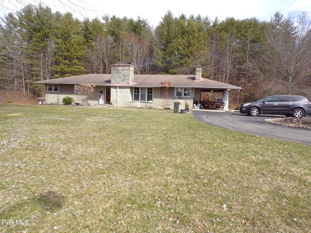 view of front of house featuring driveway, a carport, a chimney, and a front yard