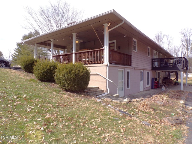 view of side of home featuring stairway, a lawn, a ceiling fan, and a deck