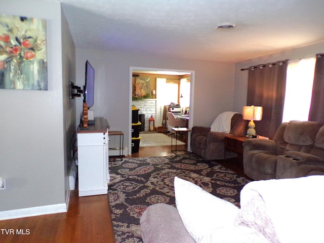 living room featuring a baseboard heating unit, wood finished floors, and baseboards