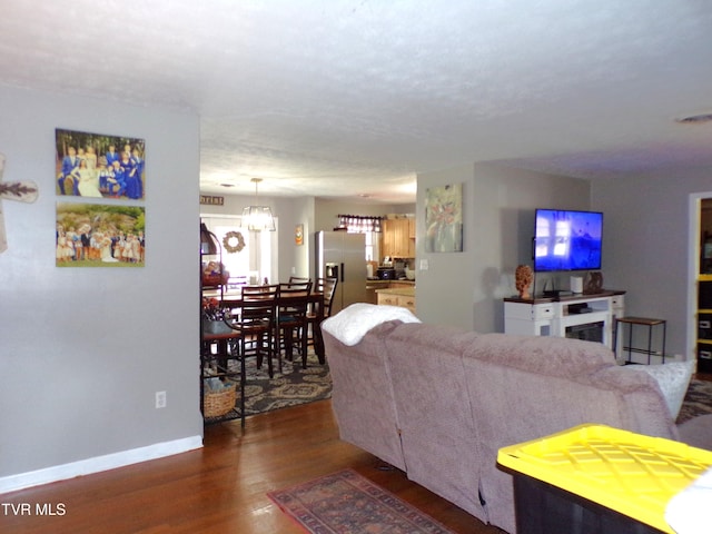 living area featuring visible vents, a notable chandelier, wood finished floors, and baseboards