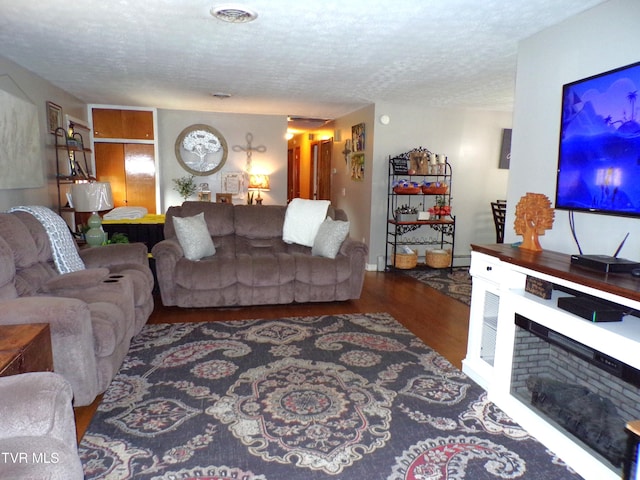 living room with a fireplace, wood finished floors, and a textured ceiling