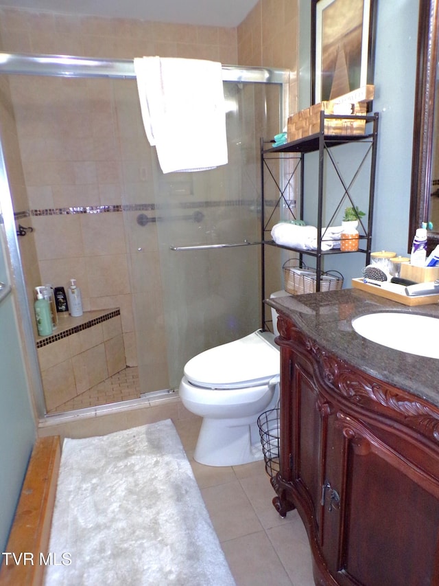 bathroom with tile patterned flooring, toilet, vanity, and a stall shower