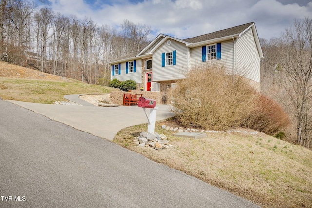 view of front of house featuring brick siding, driveway, and a front lawn