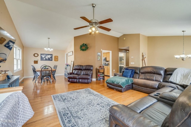 living area featuring high vaulted ceiling, light wood-style flooring, ceiling fan with notable chandelier, and baseboards