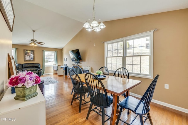 dining area featuring baseboards, light wood-style floors, ceiling fan with notable chandelier, and vaulted ceiling