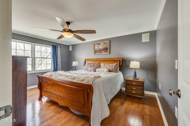 bedroom featuring visible vents, hardwood / wood-style flooring, baseboards, and ornamental molding