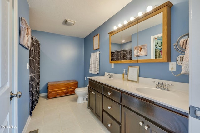 full bathroom featuring visible vents, toilet, double vanity, tile patterned floors, and a sink