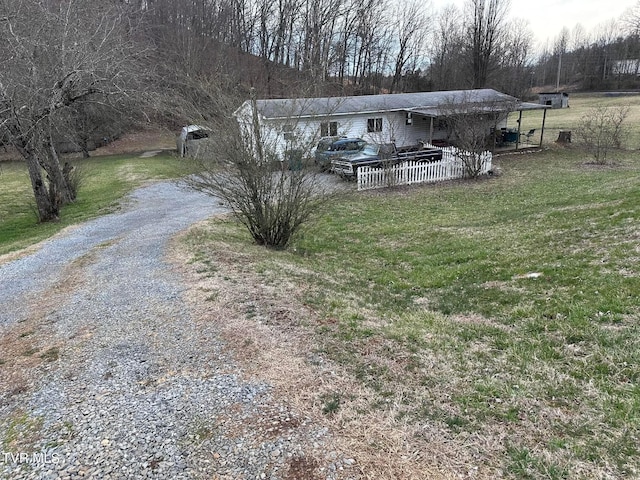 view of front of house with gravel driveway and a front lawn