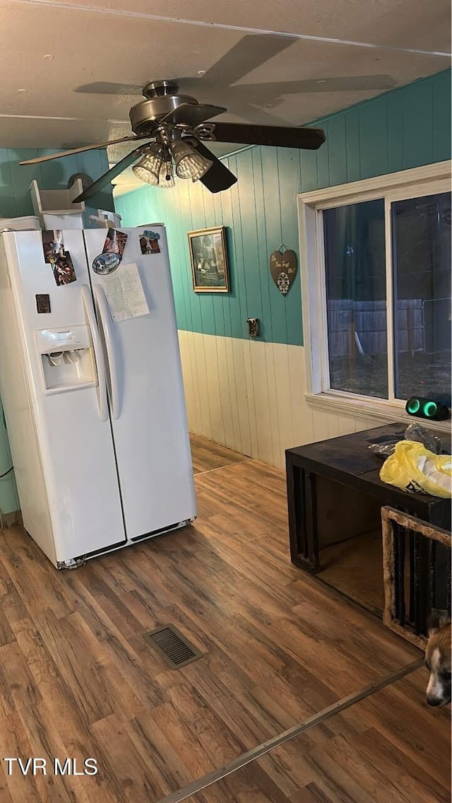 kitchen featuring visible vents, wood finished floors, a ceiling fan, and white fridge with ice dispenser