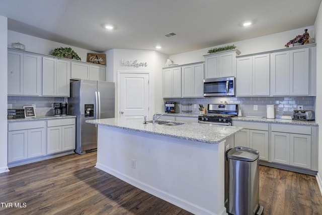 kitchen featuring light stone counters, dark wood-style floors, an island with sink, a sink, and stainless steel appliances