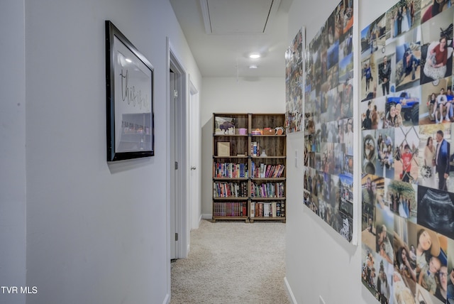 hall featuring carpet flooring, attic access, and baseboards