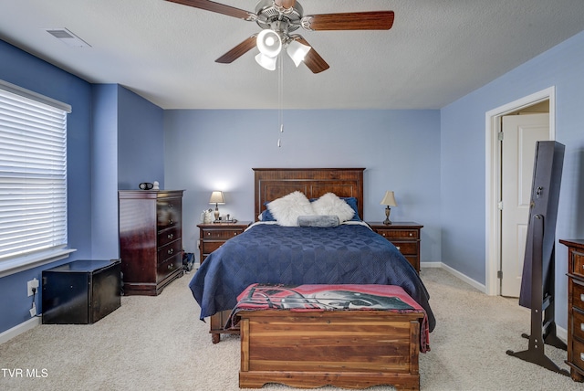 carpeted bedroom with a textured ceiling, baseboards, visible vents, and ceiling fan