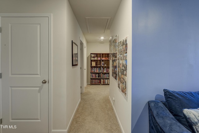 corridor with attic access, light colored carpet, and baseboards