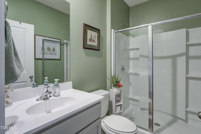 bathroom featuring a shower stall, toilet, and vanity