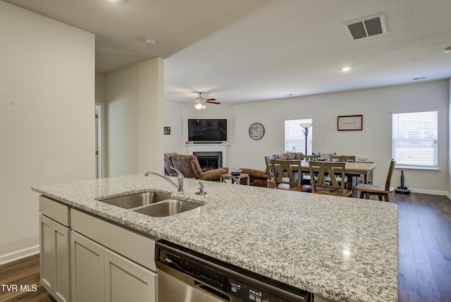 kitchen featuring visible vents, a sink, a fireplace, stainless steel dishwasher, and a kitchen island with sink