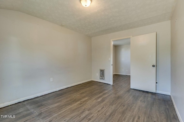 spare room with heating unit, wood finished floors, baseboards, and a textured ceiling