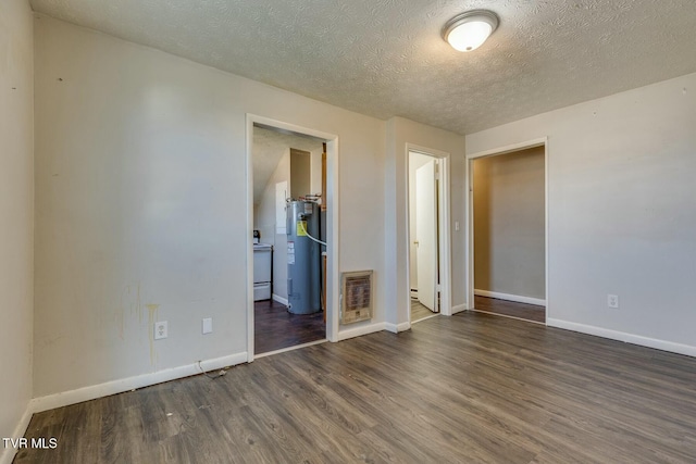 empty room featuring visible vents, electric water heater, baseboards, wood finished floors, and a textured ceiling