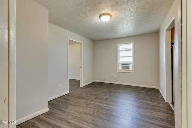 spare room featuring dark wood finished floors, cooling unit, baseboards, and a textured ceiling