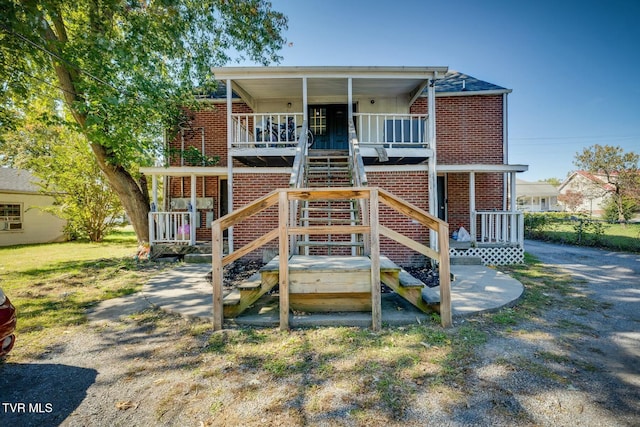 rear view of property featuring brick siding and covered porch