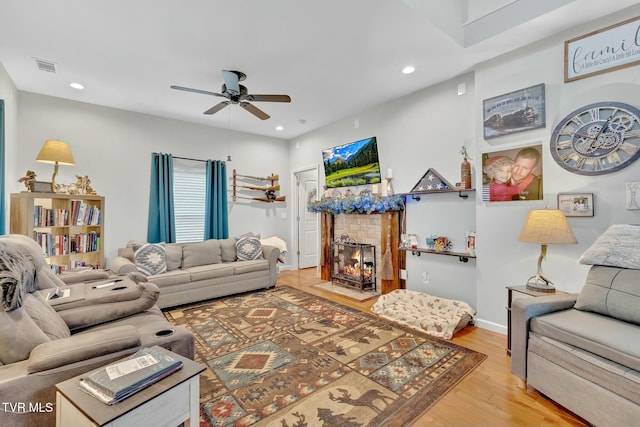 living area featuring light wood-type flooring, visible vents, a fireplace with flush hearth, recessed lighting, and ceiling fan