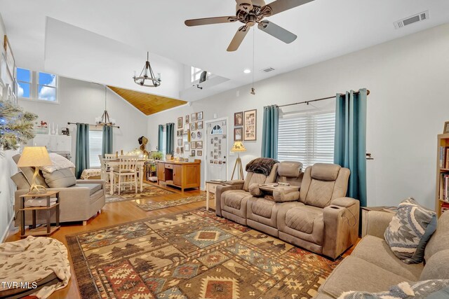 living area featuring visible vents, ceiling fan with notable chandelier, light wood-type flooring, and lofted ceiling