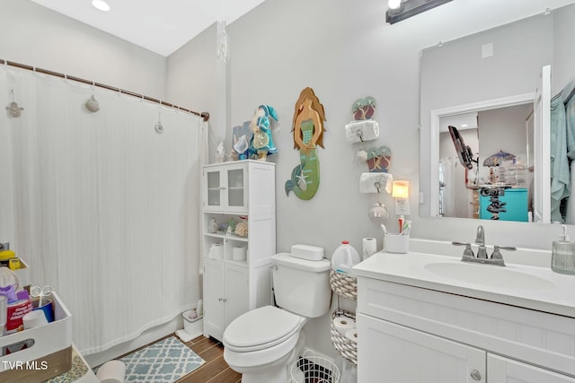 full bath featuring a shower with shower curtain, toilet, wood finished floors, and vanity