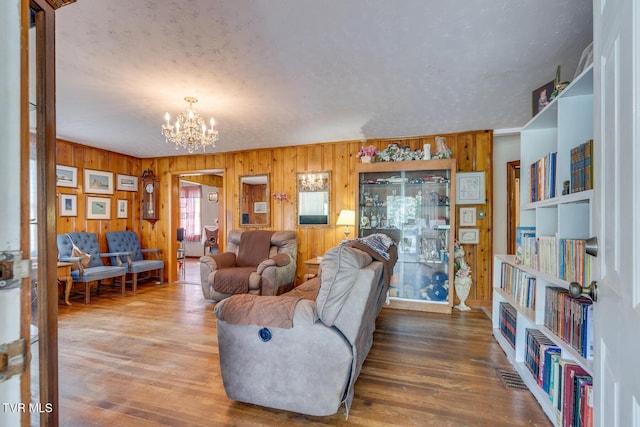 living room featuring wood finished floors, wood walls, and a chandelier