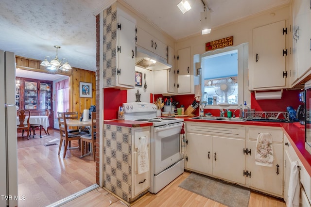 kitchen with wooden walls, under cabinet range hood, light wood-style flooring, white range with electric stovetop, and a sink