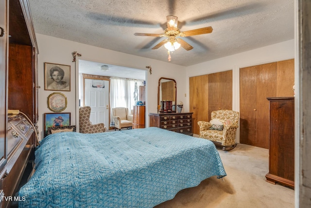 carpeted bedroom featuring a ceiling fan, multiple closets, and a textured ceiling