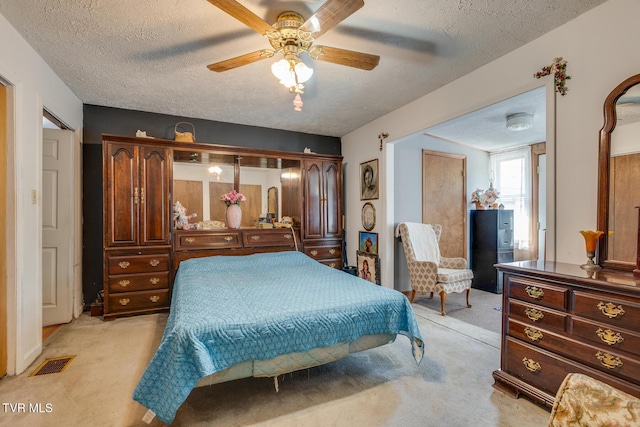 bedroom featuring visible vents, light colored carpet, and a textured ceiling