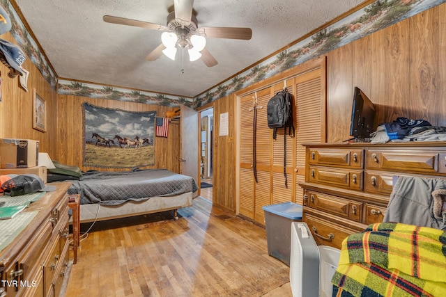 bedroom with wood walls, a textured ceiling, crown molding, and light wood-style floors