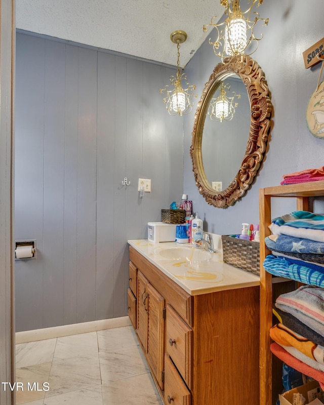 bathroom featuring vanity, an inviting chandelier, marble finish floor, and a textured ceiling