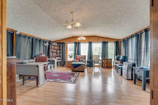 interior space featuring lofted ceiling, a textured ceiling, an inviting chandelier, and wood finished floors